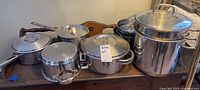 Overview of metal pots with lids and mixing bowls displayed on a wooden surface.
