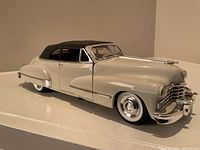 Front right angle showing the white body, chrome trim, clear windows, and black soft top roof of the Cadillac model car.