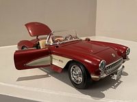 Front side angle of the red 1957 Corvette die-cast model with open left door and hood, showing detailed front grille and interior.