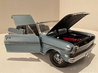 Front-side view of the die-cast 1963 Chevrolet Nova with the driver's door, hood, and trunk open, showing engine detail and interior upholstery.