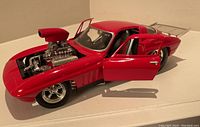 Front side view of red 1966 Corvette dragster die-cast model showing open hood with visible engine and open driver and passenger doors.