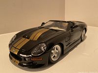 Front-right angled view showing black and gold Shelby Series 1 die-cast car with closed hood and doors.