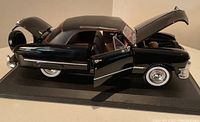 Black 1:18 scale 1950 Ford Maisto diecast model car with driver door, hood, and trunk open showing details.
