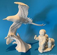 Photo showing both the Bermuda Longtail bird figurine and the Snow Baby Cherub figurine side by side.