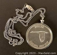 Front of silver dollar coin pendant showing flying Canada goose design dated 1867-1967, attached to silver-tone chain.