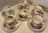 Top down view of six porcelain teacups paired with matching saucers, displaying various floral patterns and gold trim