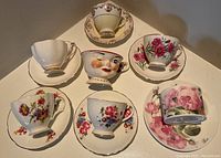 Top view of all 7 teacups each with matching saucers showing decorative details and floral patterns.