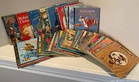 Photo showing 36 vintage Little Golden Books fanned out on a shelf, including titles with Christmas themes such as Rudolph the Red-Nosed Reindeer and Baby's Christmas.