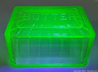 Top and side view of the rectangular translucent green uranium glass lid embossed with 'BUTTER'.