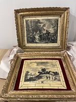 Pair of two framed antique engravings on tile showing detailed periods scenes, placed on a surface with white tissue paper for protection.