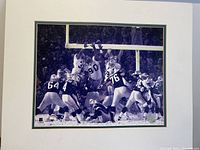 Full front view of framed black and white football game photograph with visible authenticity logos at bottom