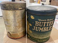 Blue metal 'Uneeda Bakers Butter Jumbles' tin seen from side showing branding and condition.
