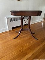 Front side view of the closed console table showing the decorative leg structure and brass tips.
