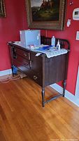 Side view of vintage dark wood console table showing two center drawers and long bottom drawer with side cabinet door.