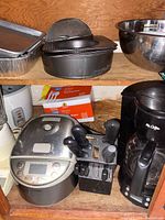 Photo of kitchen shelf with metal baking trays, colander, metal mixing bowls, rice cooker, knife block, Mr. Coffee drip coffee maker