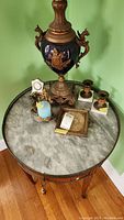 Full view of round marble tile top with decorative wire tray edge and various decorative items placed on top.