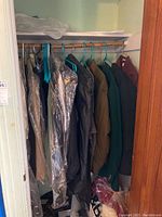 Closet rack with various men and women jackets including puffer coats, wool blazers, and covered dry-cleaner coats