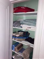 Closet shelves with folded bed linens and blankets in various colors and patterns