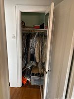Full view of closet door showing men's jackets and suits partially visible inside and hanging on wooden hangers.