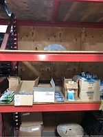 Warehouse shelf with multiple boxes of aquarium supplies including floating thermometers, chillers, and air stones.
