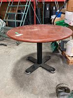 Front view of round wood top dining table showing surface scratches.