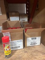 Two open cardboard boxes containing multiple red-capped aerosol cans labeled 'Go Green Doktor Doom' total release fogger insecticide.