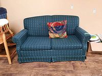 Front view of blue Sears loveseat with patterned upholstery, including a multicolored decorative side cushion.