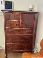 Front view of the 1920's mahogany highboy dresser showing drawers and cabinet door with original brass pulls.