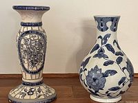 Blue and white mosaic candle holder and ceramic vase placed side by side on wooden surface against white wall.