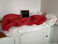 Large folded red and white Canadian flag on white surface with a sign 'Lot 98'.