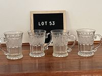 Four vintage pressed glass cider mugs displayed in a row, showing the set of 4 with consistent decorative pressed glass pattern and handles.