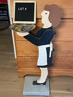 Side angled view of wooden maid folk art figure holding the serving tray showing profile and apron bow detail