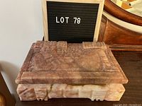 Front view of rectangular carved marble box with lot 78 sign behind it, showing the multi-colored marble and thickness of the box.