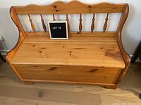 Front view of the pine storage bench showing the lid and spindle backrest.