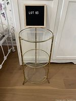 Front view of three-tier round glass shelf planter with brass frame, showing the overall structure and condition.