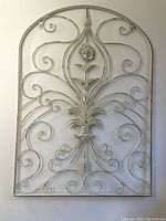 Front view of metal wire wall decoration showing overall ornate floral and scrollwork design in distressed white paint.