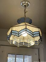 Pendant hanging light fixture mounted and lit to show stained glass shade detail.