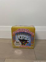 Front of sealed Beatles puzzle tin with colorful graphics and product details