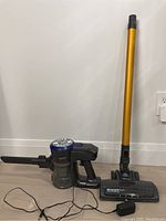 Full view of the Dibea cordless vacuum cleaner unit with detachable yellow floor brush and charger on floor against white wall.