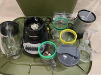 Photo showing a Black & Decker blender base with buttons, large glass pitcher, and plastic accessory parts with colored rings (green, yellow)