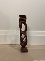Front view of the mid-century wooden abstract sculpture showing height, polished wooden texture, and inner cutouts.