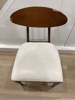 Front view of a mid-century modern wooden chair featuring an oval wooden backrest and white leather cushioned seat.