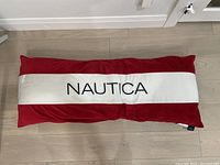 Red and white rectangular Nautica bed pillow with embroidered brand logo on white center panel