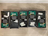 Five sealed Simms Specialty Spackling trim paint kits each containing a paint tray, roller handle, and two white mini roller covers on a wooden floor.