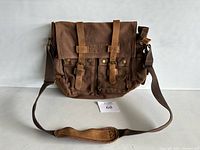 Front view of brown canvas messenger bag with leather straps and pockets showing overall condition and design.