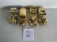 Four golden collectible model cars arranged side by side showing top view details.