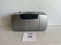 Front view of HP Photosmart 145 printer showing the HP logo and model number on silver casing, with MaxSold lot card.