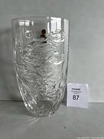Front view of clear lead crystal vase with embossed fish pattern and flower detailing, labeled with auction number.