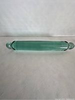 Full top view showing the entire rolling pin's green glass body and rounded glass handles at each end.