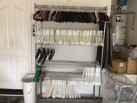 Full view of the metal rack holding multiple rows of clothes hangers arranged by type and color.
